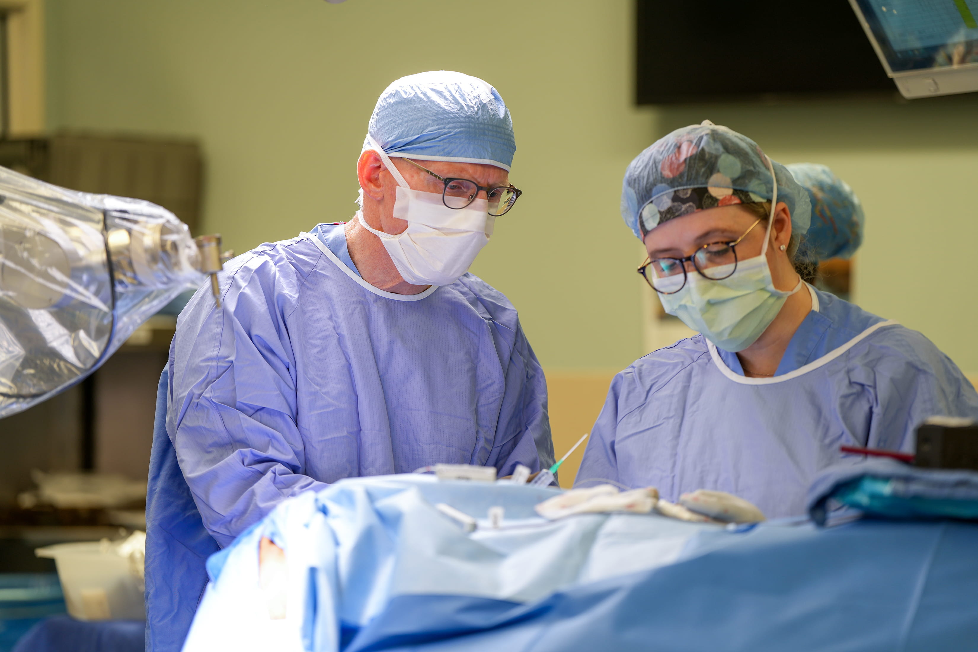 a surgeon and resident perform surgery