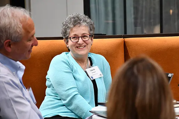 Dr. Laurie Gutmann smiling while listening to others talk