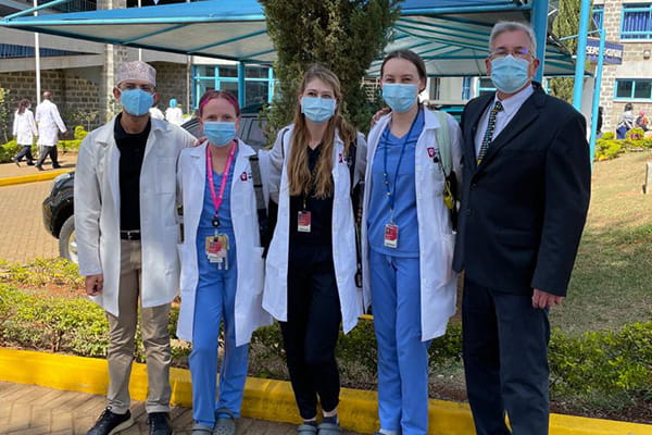 A group of neurology residents and faculty pose outside of a hospital in Kenya