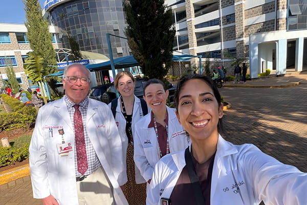 A group of neurology residents and faculty pose outside of a hospital in Kenya