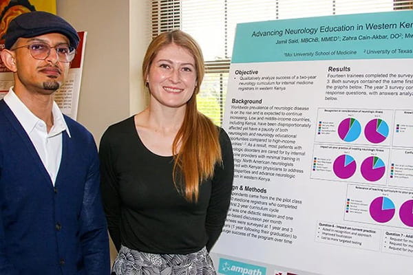 Jamil Said and Katie Hutchins pose in front of a poster presentation 