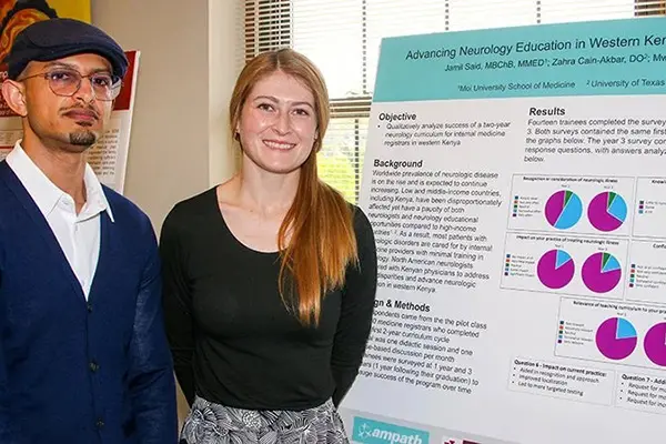 Jamil Said and Katie Hutchins pose in front of a poster presentation 