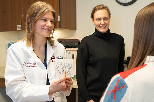 Haley Basinger shows a patient information on a card. Ann Jones stands behind her looking at the patient.