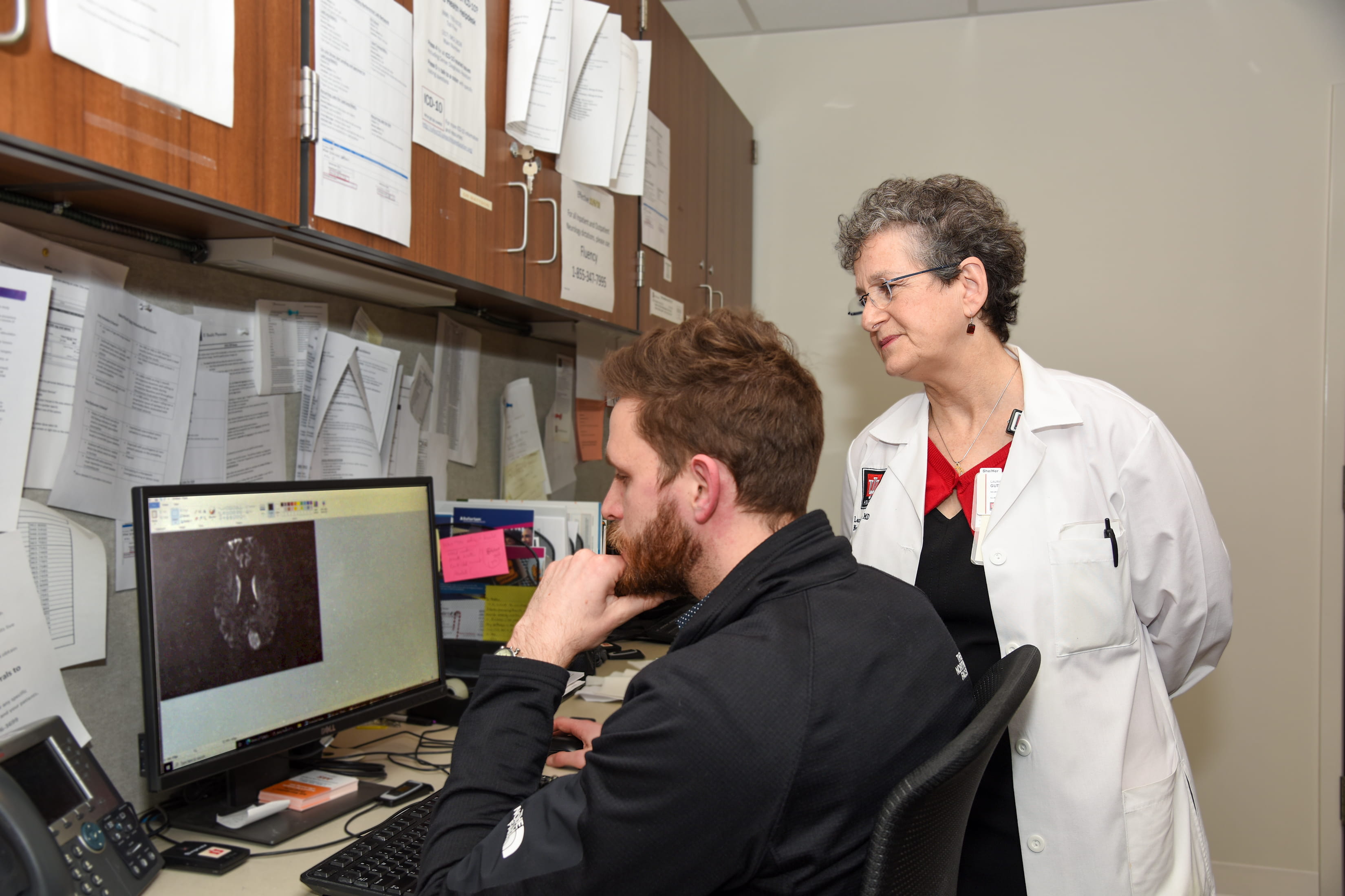a faculty member and resident look at a computer screen