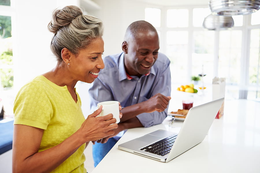a black middle-aged couple look together at a computer screen