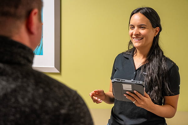 A neurologist holds an iPad while talking to a colleague 