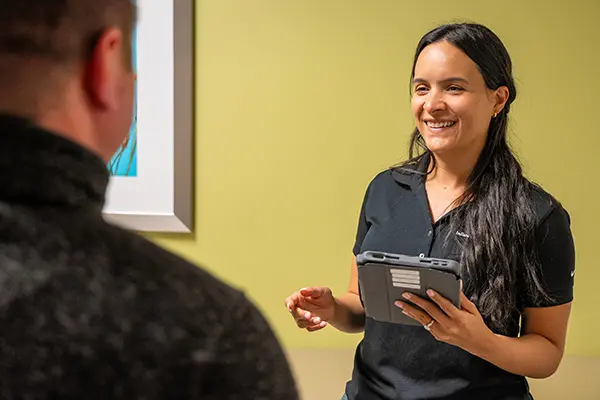 A neurologist holds an iPad while talking to a colleague 
