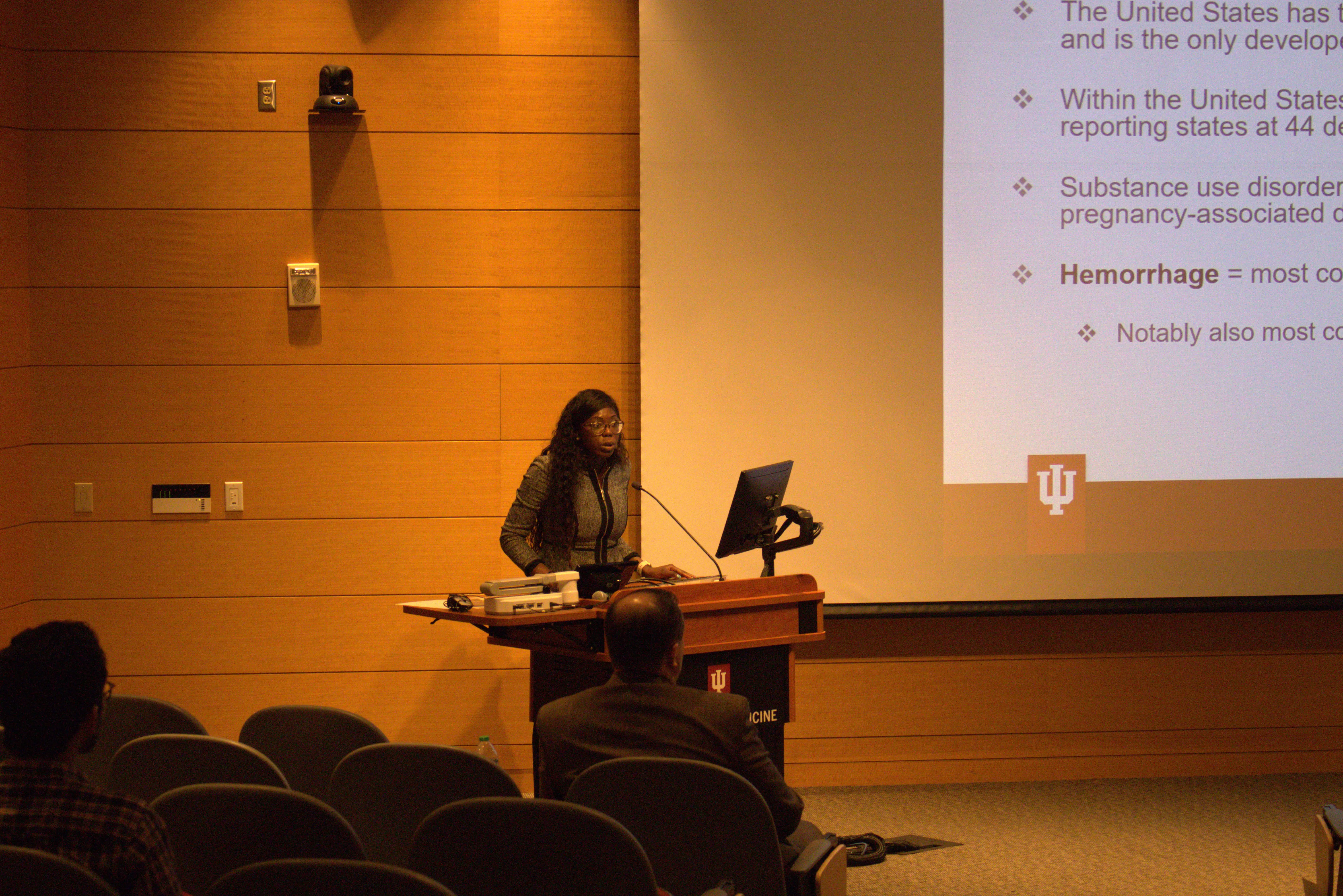 Dr. Kemi Ogunmuko stands at the lectern in front of her audience in the auditorium