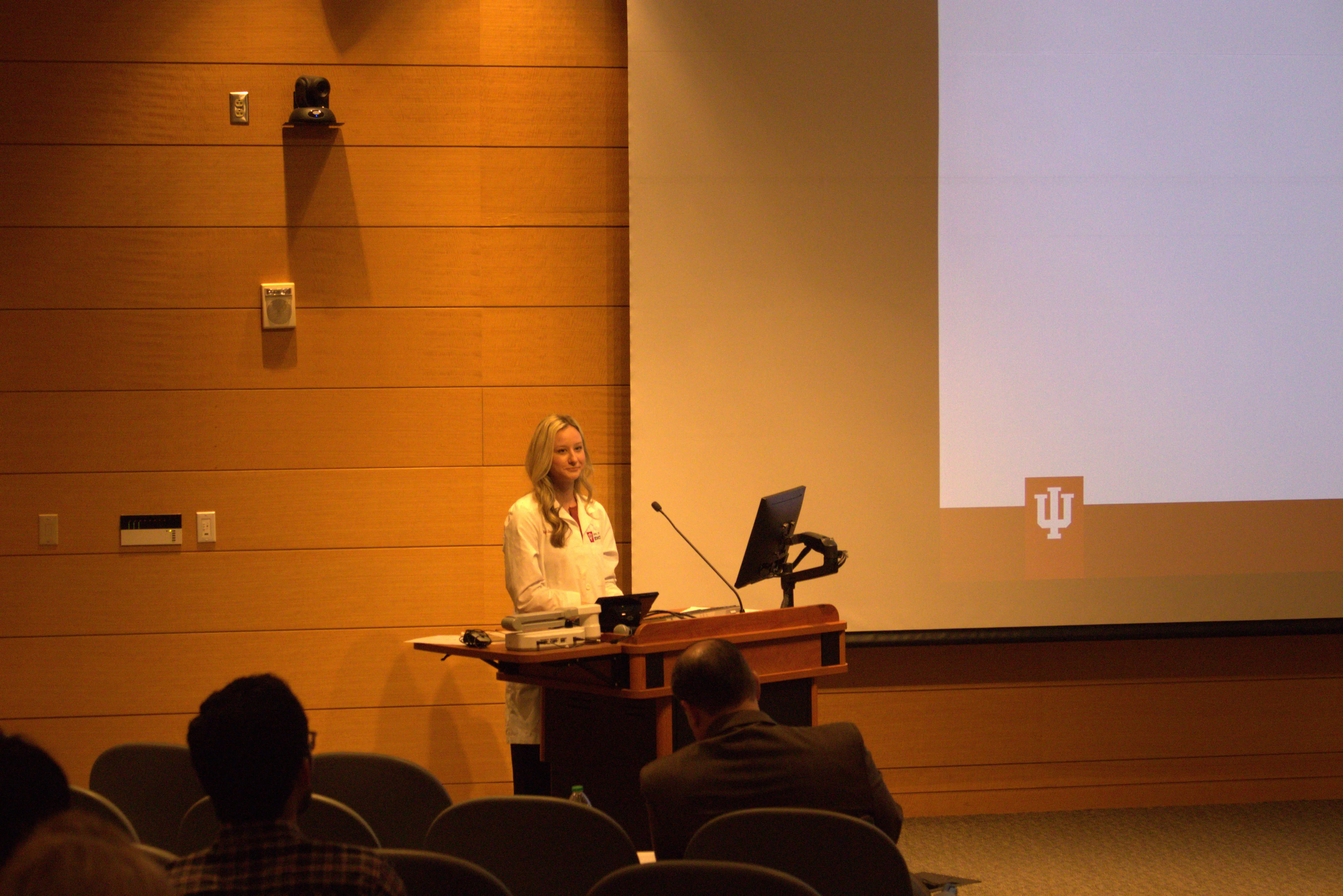 Dr. Paige Schultheis stands at the lectern in front of her audience