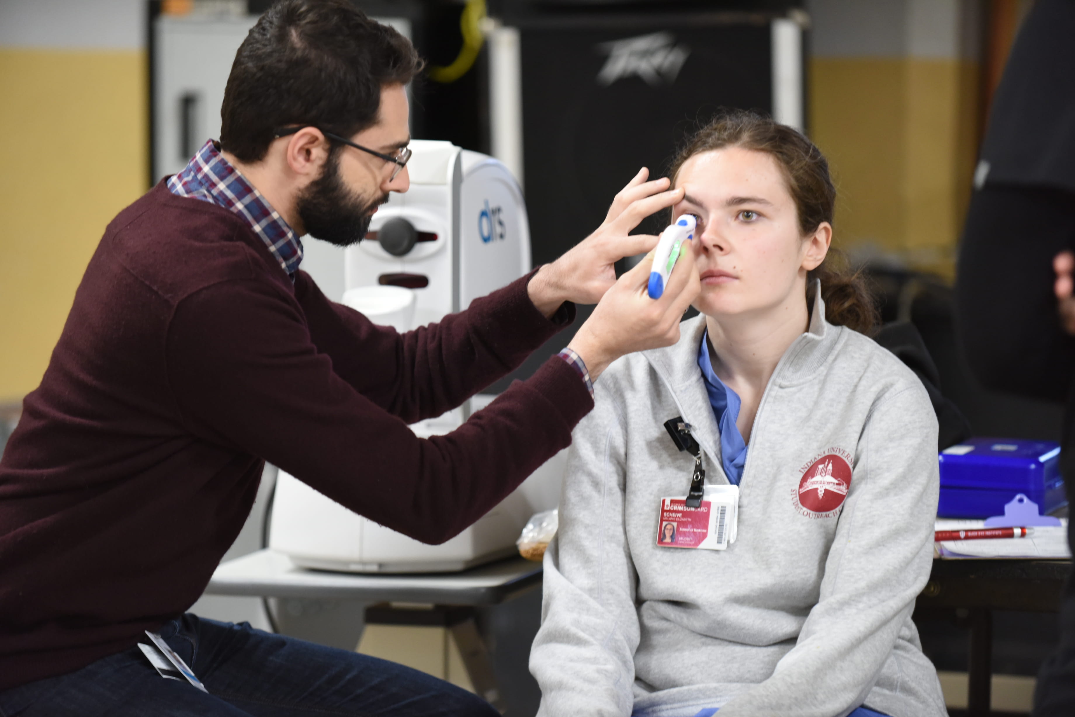A resident conducts an eye exam on a medical student at the student outreach clinic in Indianapolis. 