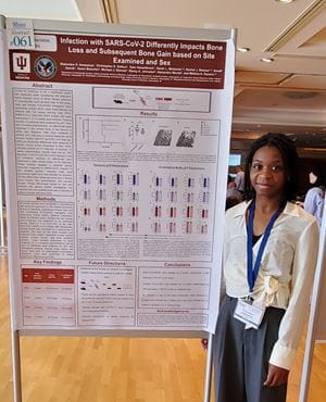 Awosanya stands beside her poster Ola Awosanya stands aside her award-winning poster