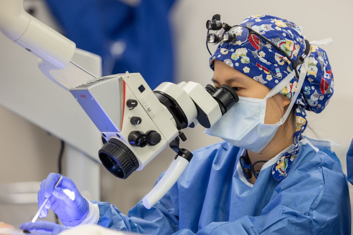 A surgeon in scrubs uses a magnifying device in the operating room