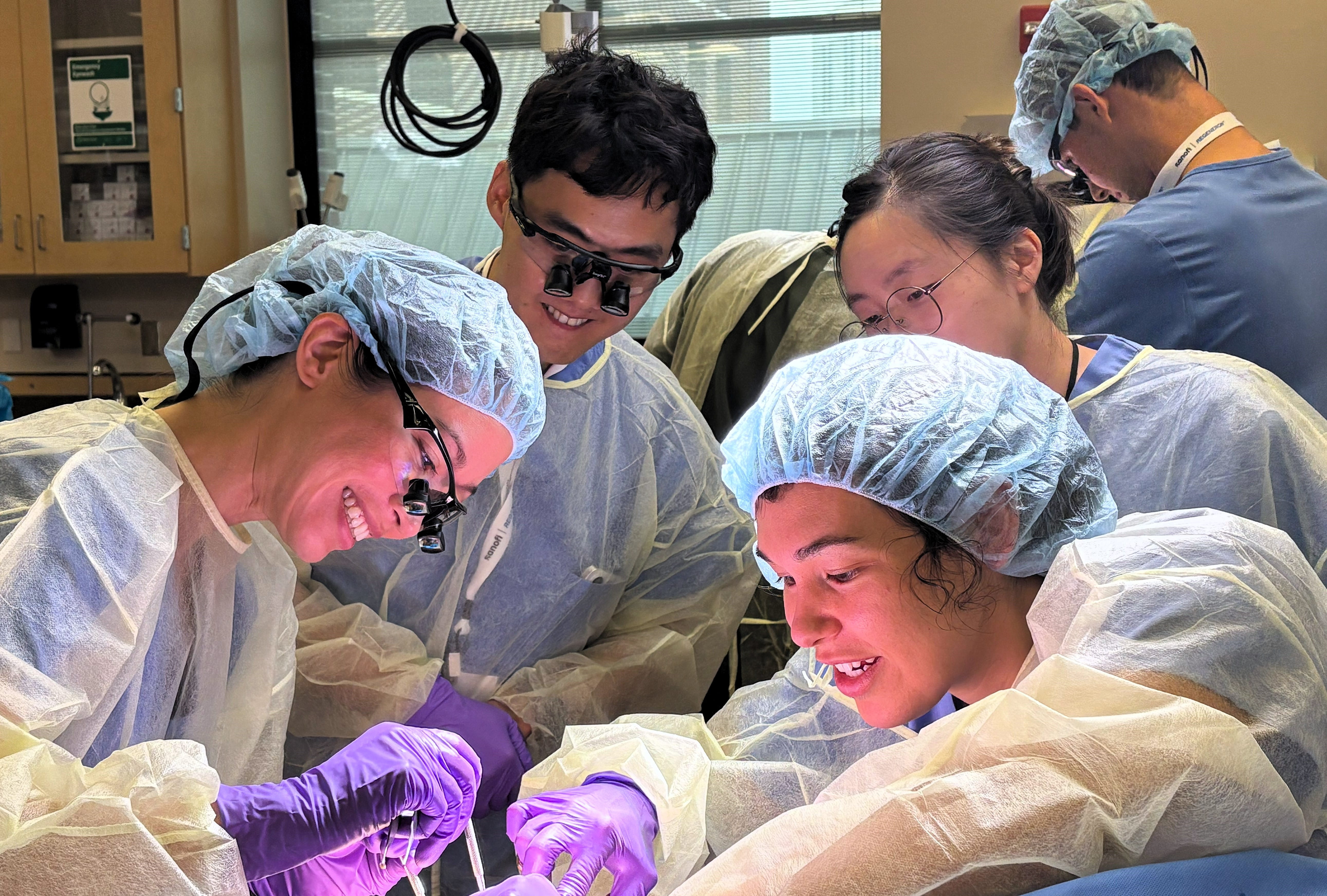 Trainees in scrubs working in surgical skills lab