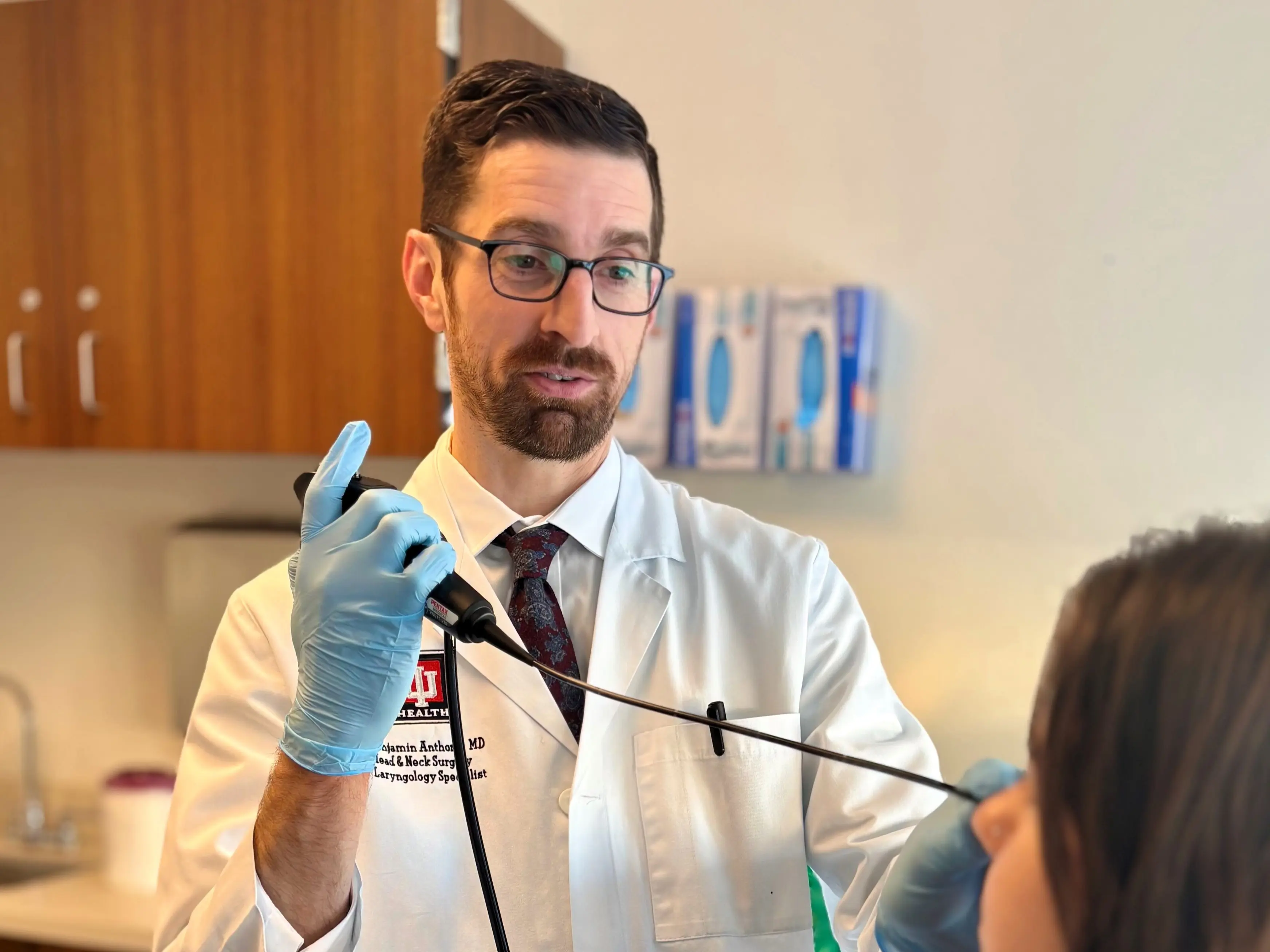 Healthcare provider in a white coat speaks with a patient in an exam room