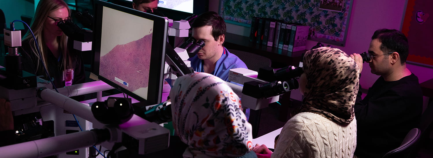 Students sitting at multiheaded scope in purple light