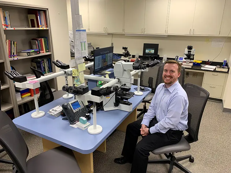 Tim sits in front of his microscope