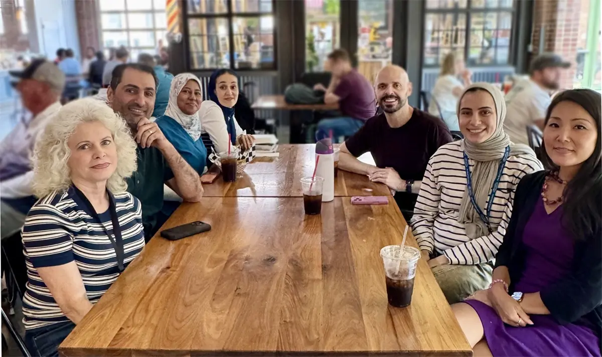 a group of smiling people sit around a table at a restaurant