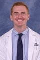 Nick wearing a lab coat and tie with short red hair