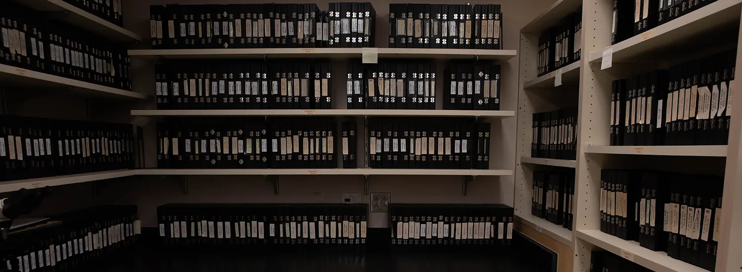 Rows of neatly organized binders line the shelves of an archival storage room, each labeled and carefully cataloged. The scene captures the commitment to preserving valuable records, ensuring easy access to historical data for future research and reference.