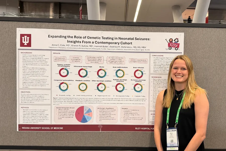 Photo of a woman with a black shirt standing in front of a research poster