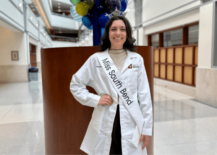 Rachel Ramos wearing her Miss South Bend crown and sash with her IU School of Medicine lab coat