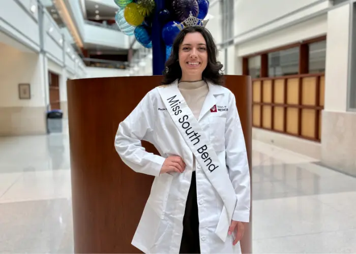 Rachel Ramos wearing her Miss South Bend crown and sash with her IU School of Medicine lab coat