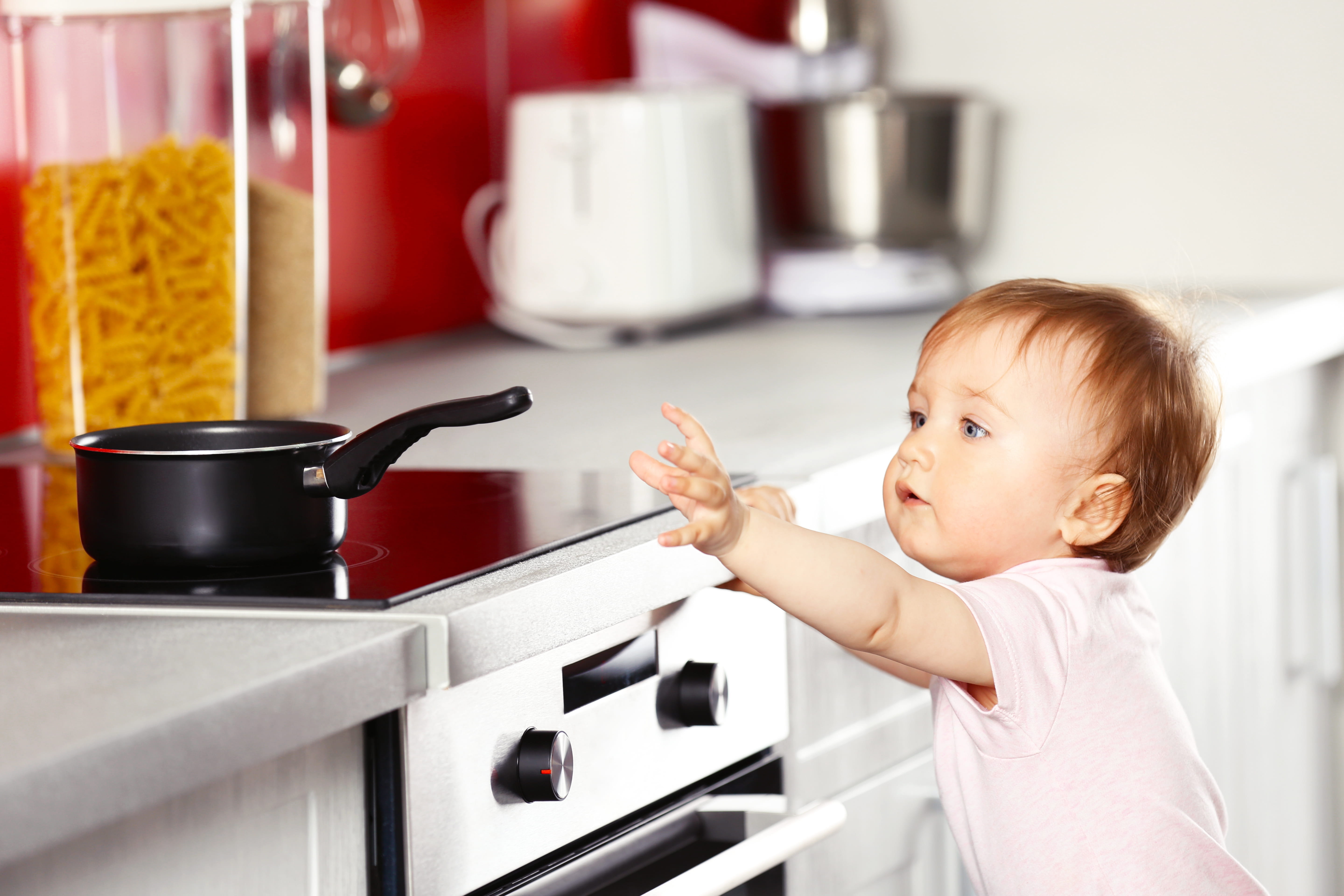 Child reaches for pot on stove