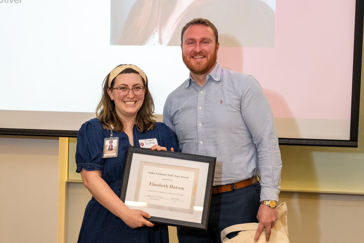 Elizabeth Hutson holds an award and smiles at the camera