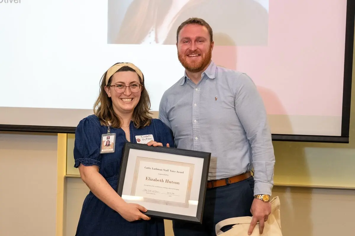 Elizabeth Hutson holds an award and smiles at the camera