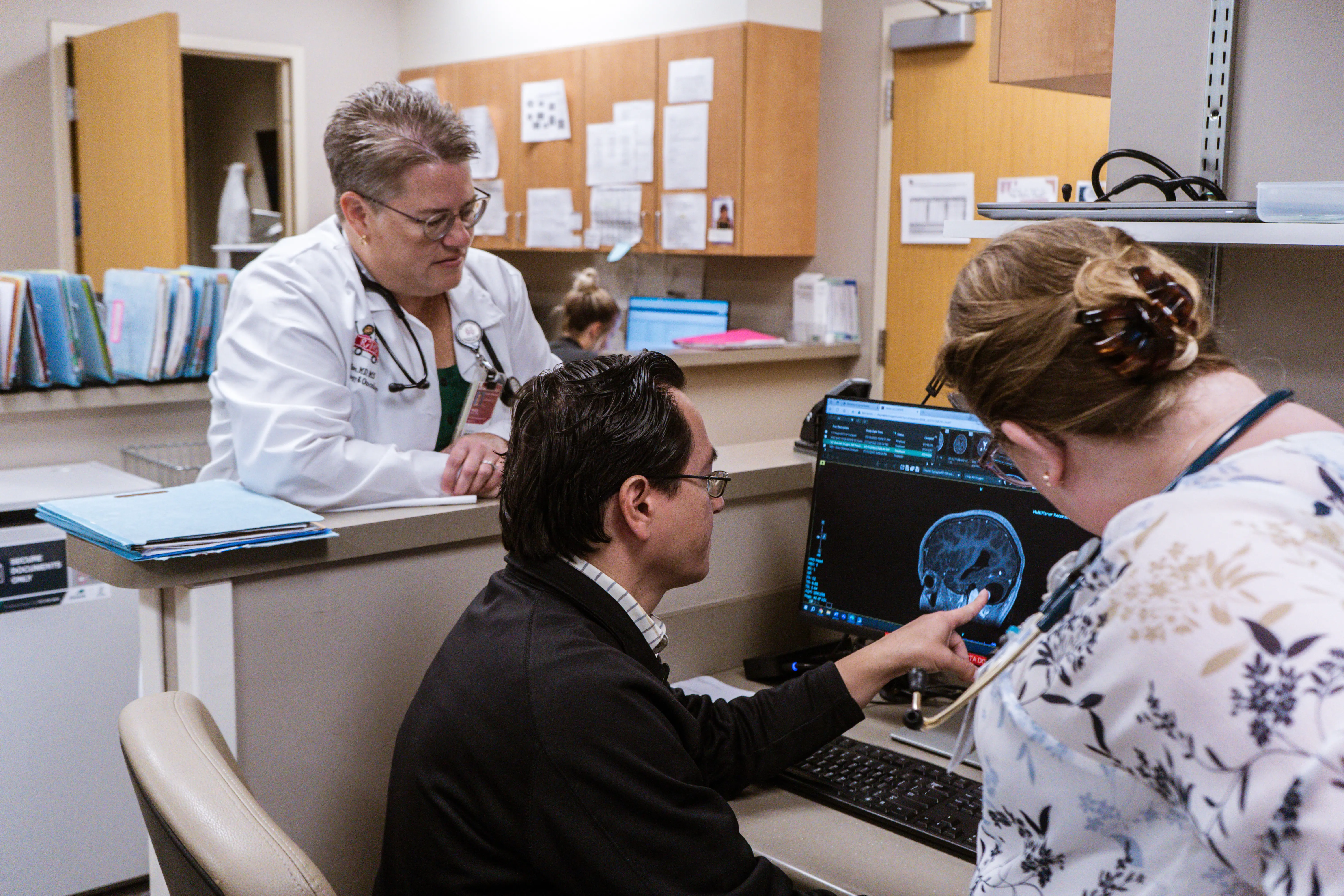 Three pediatric hematology clinical team members looking at a medical scan on a computer screen