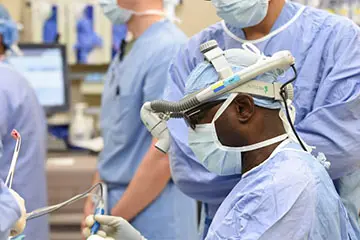 Dr. Yekinni in medical protective garb working on a surgery alongside surgical colleagues