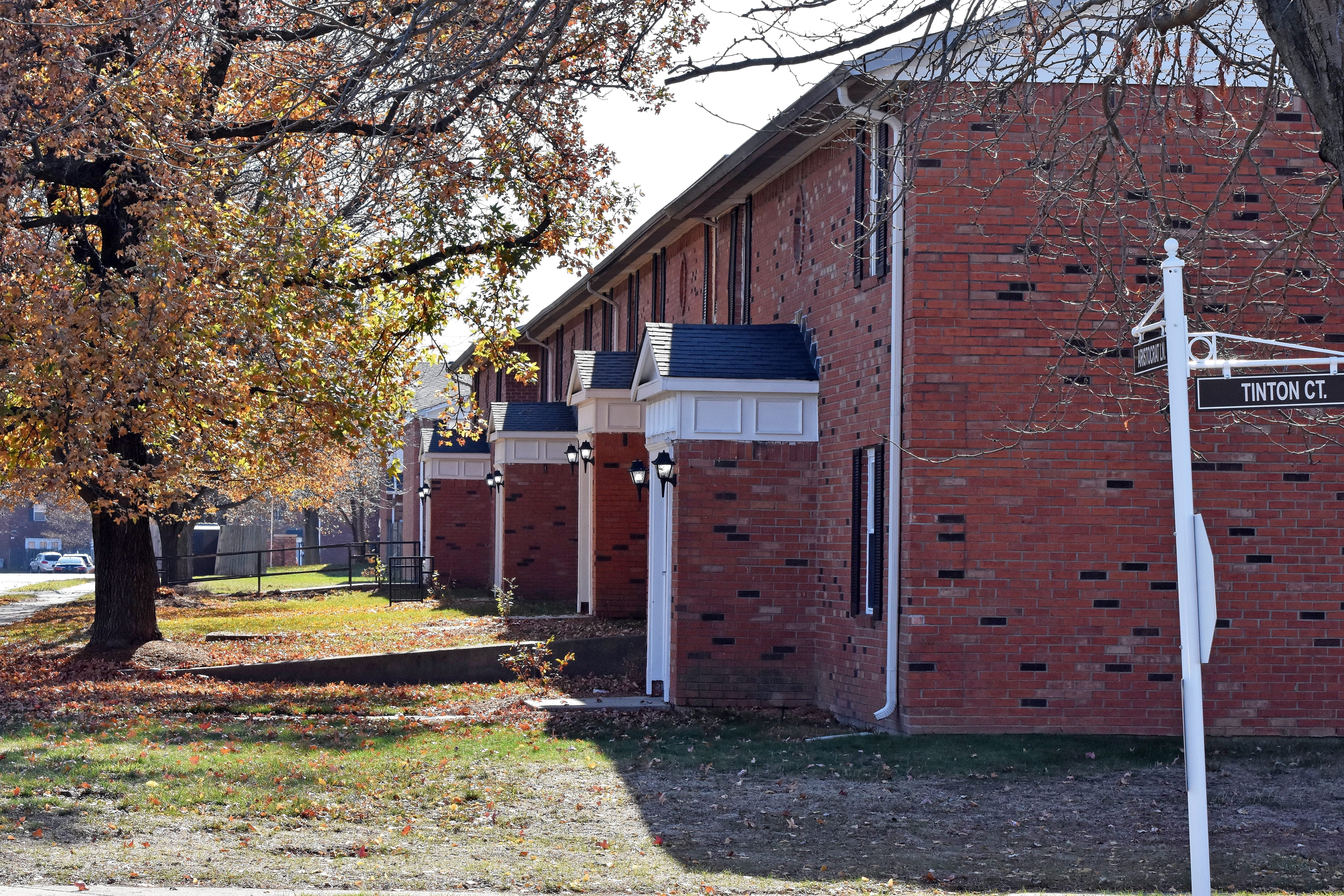 a brick apartment building with autumn leaves and trees outside