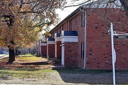 a brick apartment building with autumn leaves and trees outside
