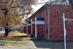 a brick apartment building with autumn leaves and trees outside