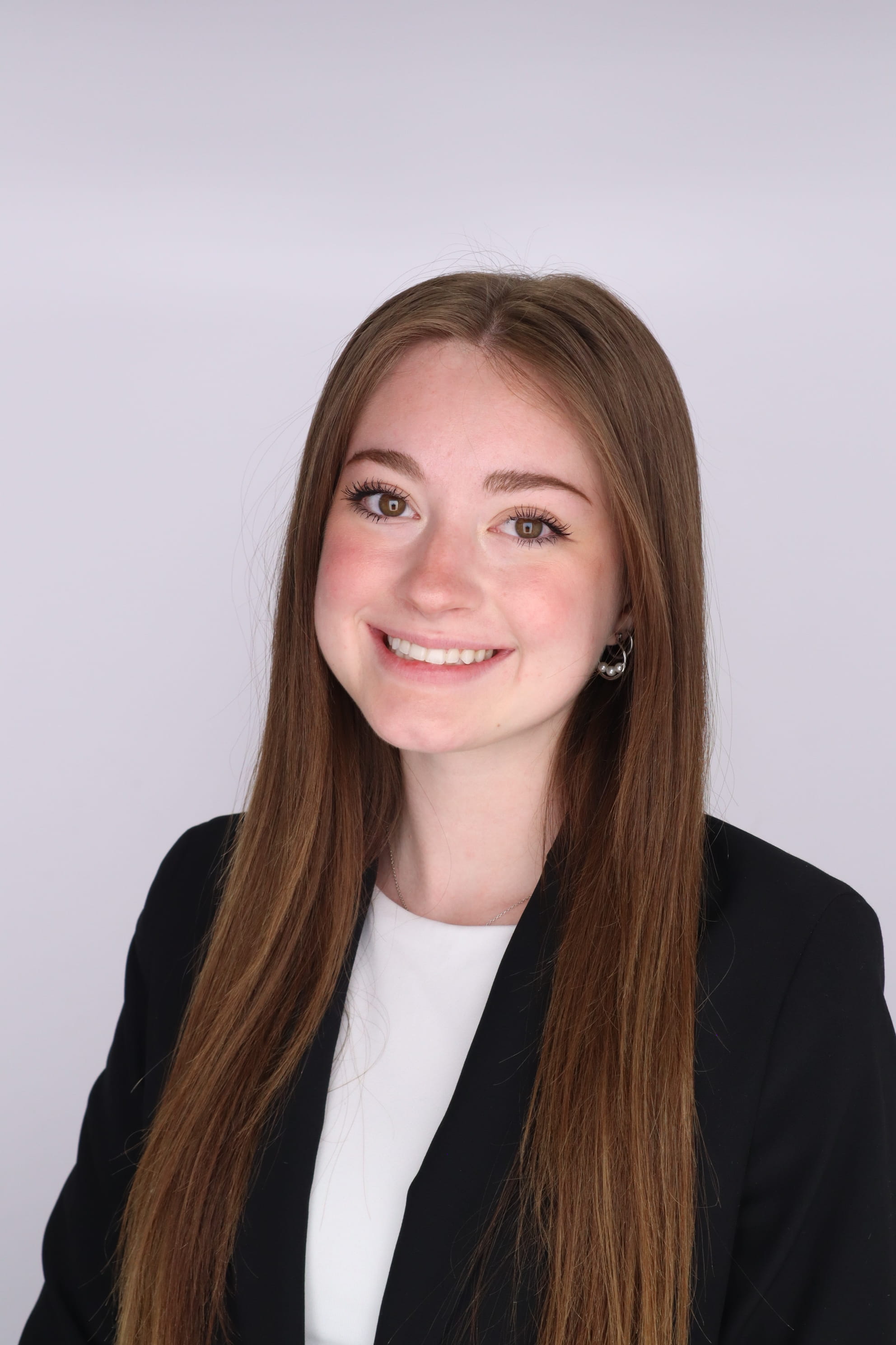 A picture of Olivia Laufer in a dark jacket on a grey background.