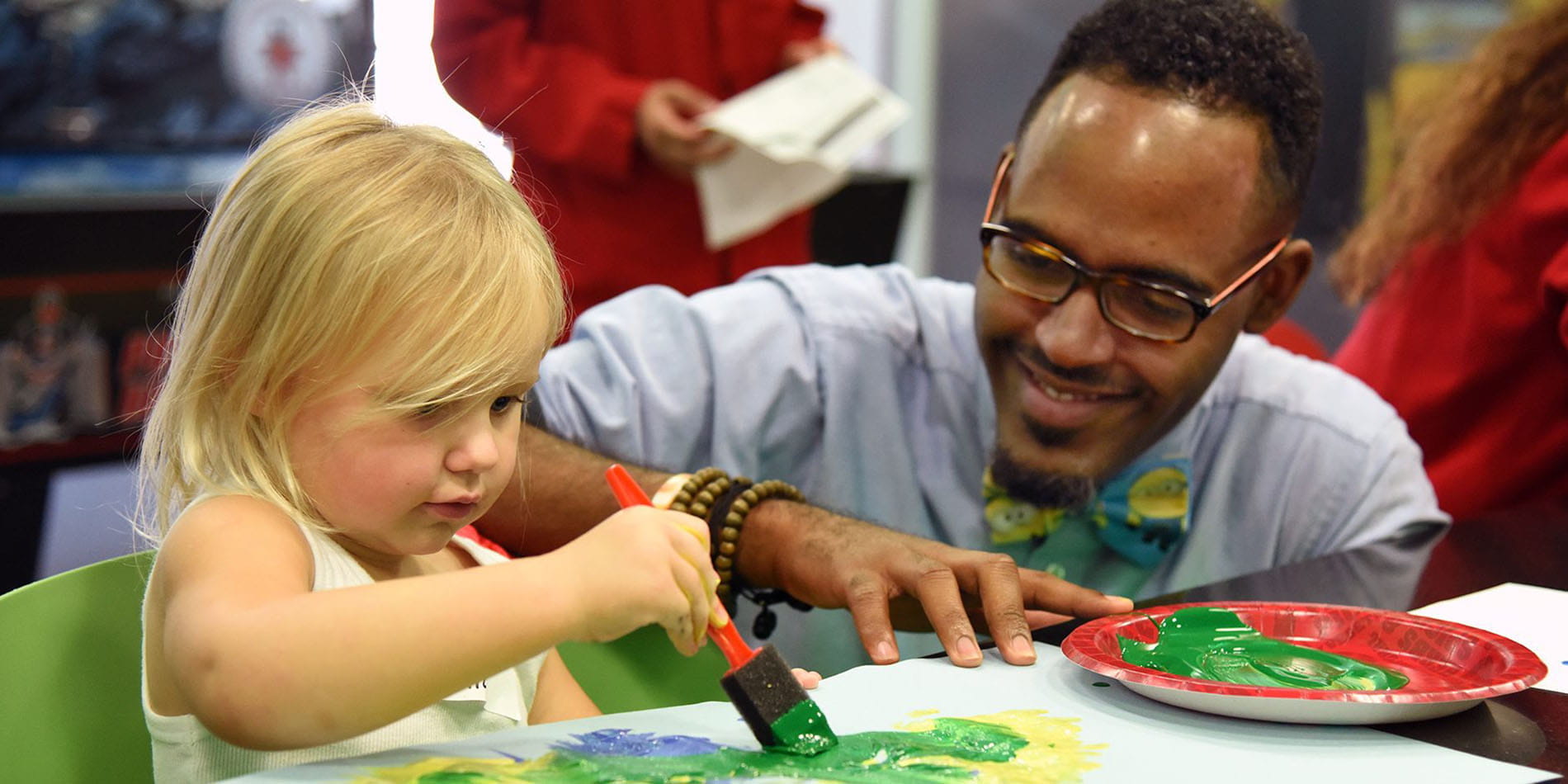 a physician and young patient work on an art project