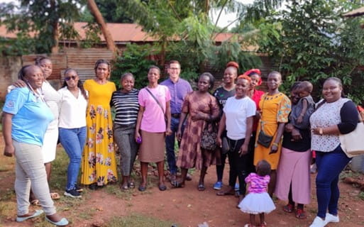 A large group of mothers and Jimmy Carlucci pose for a photo outside in a tropical climate