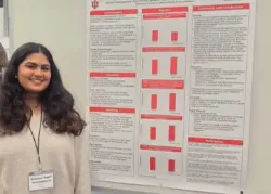 Sam Beeraraghavan, on IU pre-med track, standing next to a poster at the Purdue Autism Conference