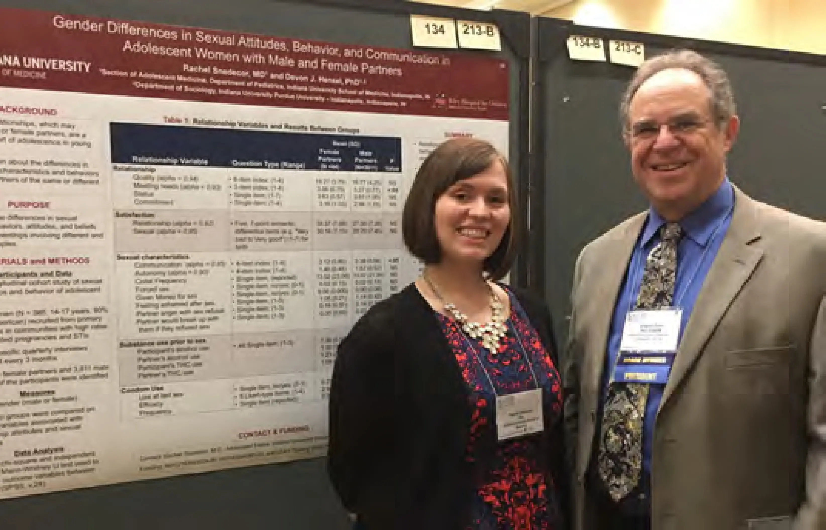 Two researchers stand in front of their research poster