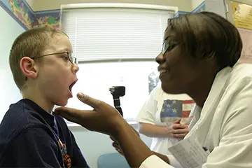 Physician checks for throat infection in pediatric patient. 