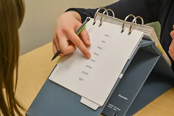 Finger pointing to a word from a list of words on a notepad