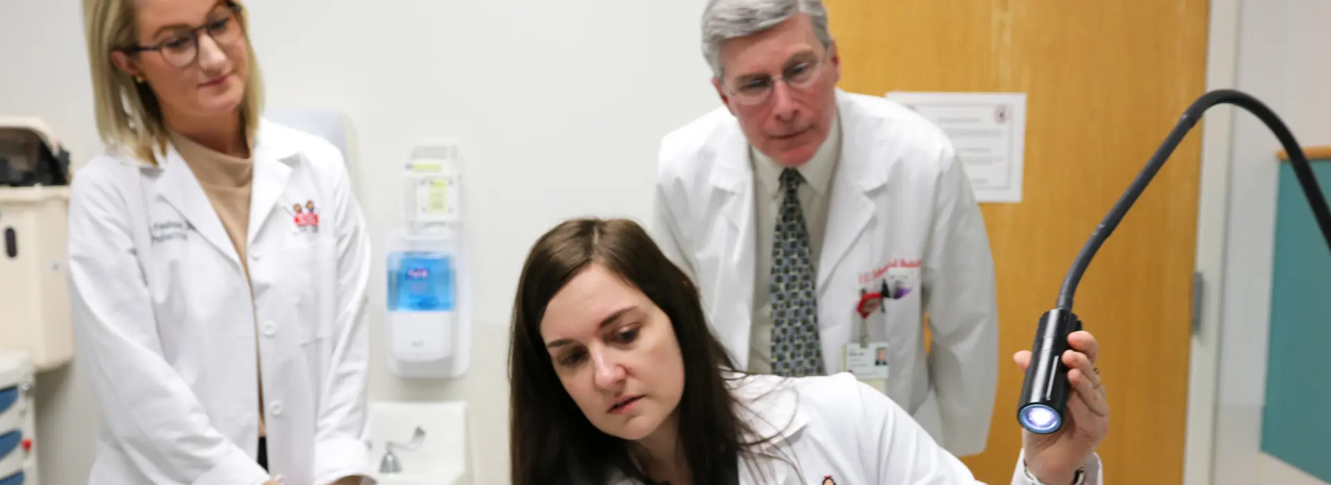 Three faculty examine patient. 