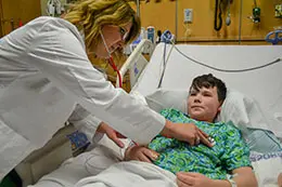 Doctor monitoring a child's heart while he is in a hospital bed