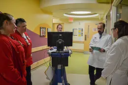 Four members from the critical care team gathered in a hospital hallway discussing patient care