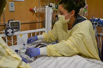 Pediatric Cardiac Intensive Care clinician working with a patient in a hospital bed