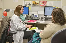 Optimized Clinical Care doctor and staff member chatting with each other near a computer