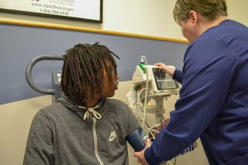 Young man getting his blood pressure evaluated by a clinician