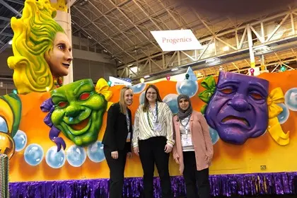 fellows pose in front of a mardi gras float at a conference