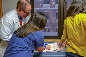 fellows examine an infant patient in the clinic