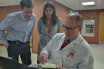 Three colleagues from the General Pediatric ID Clinic chatting and looking at a document